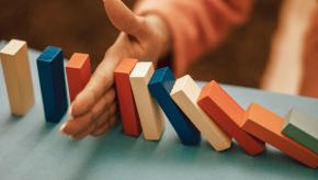 hand stopping falling dominos