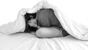 teen under covers looking anxious
