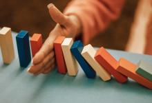 hand stopping falling dominos