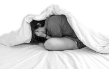teen under covers looking anxious